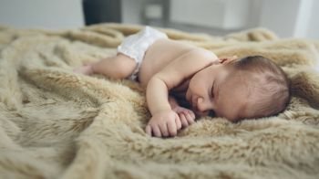Newborn baby girl sleeping lying on a blanket on the bed. Baby sleeping on a blanket