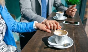 Couple of coworkers holding hands during coffee break. Couple of coworkers holding hands