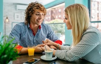 Young man and woman holding hands at a cafe. Couple holding hands at a cafe