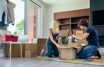 Young parents preparing moving toy box with their little son. Family preparing moving toy box