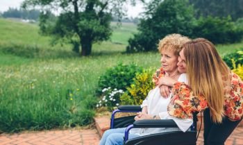 Senior woman in a wheelchair with her daughter in the garden. Senior woman in a wheelchair with her daughter