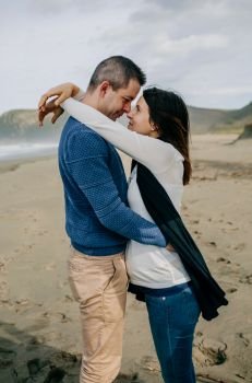 Pregnant woman hugging her partner on the beach in autumn. Pregnant woman hugging partner on the beach