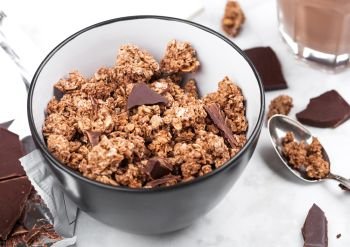 Bowl with organic chocolate granola breakfast cereal on marble background