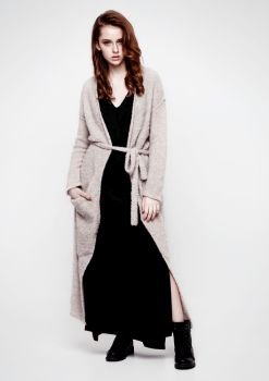 Young beautiful fashion model wearing knitwear dress and black skirt on grey background