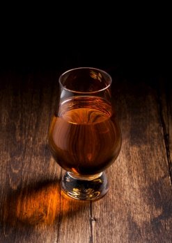 Single malt scotch whiskey in glencairn glass on wooden table background. Top view