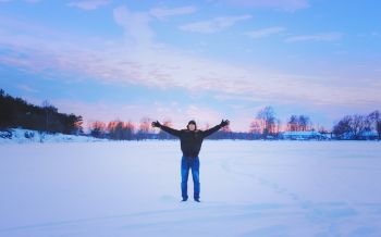 Traveler in polarized glasses with his hands raised is standing on the snowy surface of a frozen lake and enjoying the freedom and beauty of a romantic sunset. Vintage blurred filter, selective focus, space for copy.. Inspired Traveller With His Arms Raised Enjoys The Romantic Suns