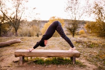 Woman practicing yoga and stretching on the park bench