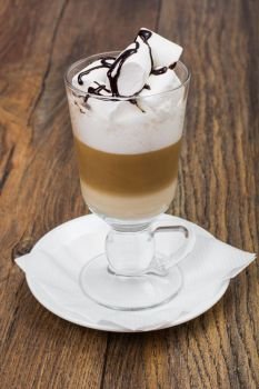 Tall glass with latte and marshmallow on wooden table. Studio Photo. Tall glass with latte and marshmallow on wooden table