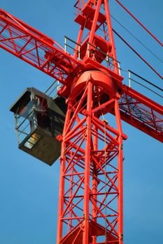 Red crane with black cabin on blue sky background in germany.