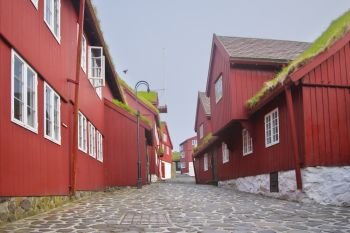 Picturesque historical centre view with typical red-painted grass-roofed timber-walled houses and cobblestone street on Tinganes in the old town of Torshavn the Captivating Capital of the Faroe Islands on Island Streymoy. Postcard motif.
