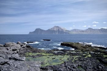 Horizontal scenery image of Faroese landscape with beautiful mountain and the North Atlantic Ocean nearby village Gjogv. Glorious sceneries of the Faroes. Postcard motif.