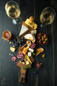Assorted cheeses with grapes, nuts and rosemary on a wooden background
