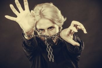 No freedom, social problems concept. Furious man with chained hands, studio shot on dark grunge background. Scared man with chained hands, no freedom