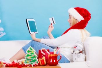 Christmas time concept. Young woman teen girl with tablet pc laptop and credit card on sofa at home doing online shopping, buying browsing for gifts, having fun. Girl with tablet credit card doing online shopping