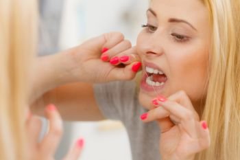Everyday oral hygiene, dentistry concept. Woman cleaning her teeth using dental floss. Woman cleaning her teeth using dental floss