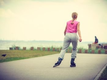 Holidays, active lifestyle freedom concept. Young fit woman on roller skates riding outdoors on sea coast, girl rollerblading on sunny day. Fit woman on roller skates riding outdoor