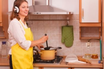 Cooking and preparing food concept. Happy relaxed beauty woman housewife chef with earphones listening music in house kitchen making dinner meal.