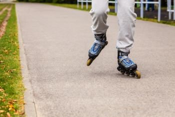 City sports and outdoor activities. Healthy lifestyle exercising and wellbeing. Free time hobby and having fun. Close up on legs in sportswear riding rollerblades.. Human legs rollerblading wearing sportswear.