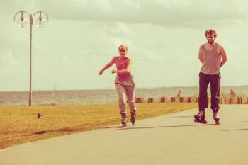 Love romance leisure outdoor fitness sport concept. Teenagers together on skates. Young girl and boy spend time riding rollerskates in park.. Teenagers together on skates.