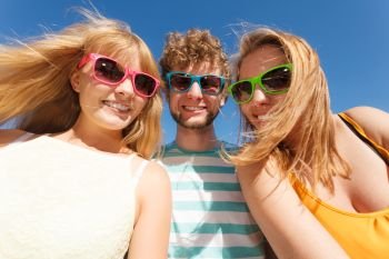 Friendship happiness summer holidays concept. Group of friends boy two girls in colorful sunglasses having fun outdoor against sky,  joy playful mood.. Group friends boy two girls having fun outdoor