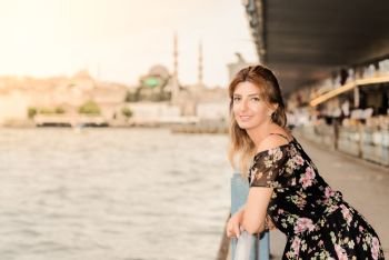 Beautiful woman in black dress stands under Galata Bridge and New Mosque view on background in Istanbul,Turkey. Beautiful woman in black dress stands under Galata Bridge