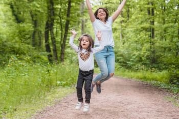 Young mom and little girl jump together together.Happy mother and daughter moments with love and natural emotion.Photo of young mother and her daughter having good time.