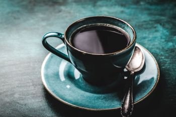 Coffee cup on a dark background with a spoon