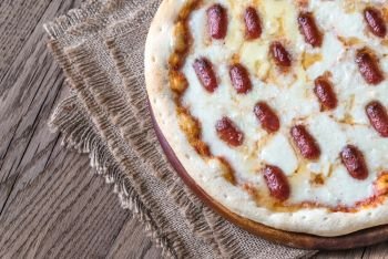 Pizza with mozzarella and salami on the wooden background