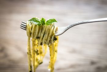 Portion of pasta with pesto sauce and basil leaf
