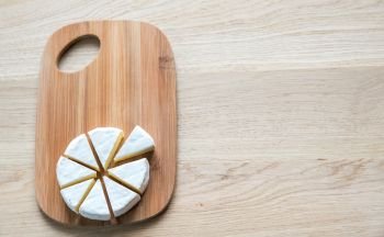 Cut head of Camembert on the wooden board