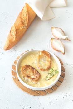 Bowl of onion soup with fresh thyme on the table