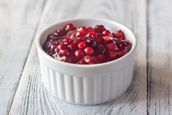 Bowl of cranberry sauce on the wooden background