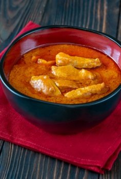 Bowl of Thai red chicken curry on the wooden background