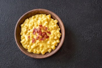 Bowl of macaroni and cheese with slices of fried bacon