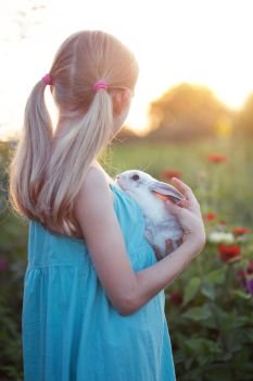 beautiful fun blond girl and rabbit on a sunny summer day
