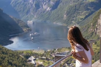 girl looks at Geirangerfjord and mountains from a viewing platform, norway
