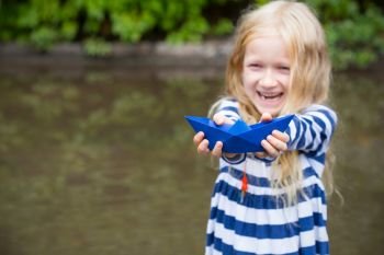 smiling girl with blue paper boat in a puddle after the rain, summer
