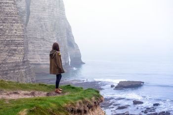 girl standing at the edge of rock in the Etretat. France
