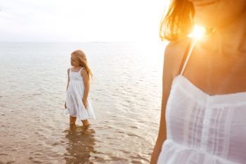 happy weekend by the sea - Mom and daughter in white dresses walking by the sea at sunset. Ukrainian landscape at the Sea of Azov, Ukraine
