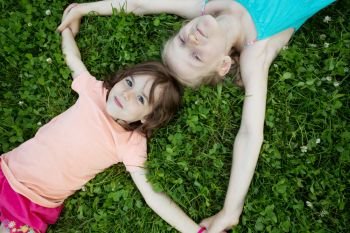 little smiling girls girlfriends on the green grass. children’s holidays
