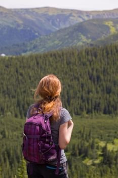 girl hiker with a backpack standing on the background of mountains and forests. Vorokhta - Ukrainian landscape.
