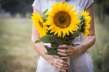 Girl holding sunflowers in hands
