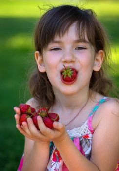 Summer - portrait of a smiling girl with a strawberry in hands
