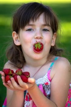 Summer - portrait of a smiling girl with a strawberry in hands
