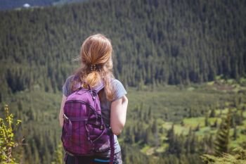 girl hiker with a backpack standing on the background of mountains and forests. Vorokhta - Ukrainian landscape.
