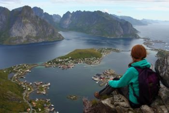 girl sitting on a cliff and looking at the Reine
