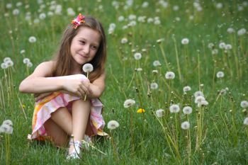 girl with dandelion and green meadow in the background
