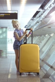 girl and beautiful yellow suitcase stands in the airport corridor
