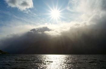 beams of bright sun shining over the water of norwegian fjord
