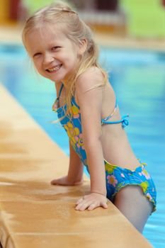 smiling little girl  near the open-air swimming pool
